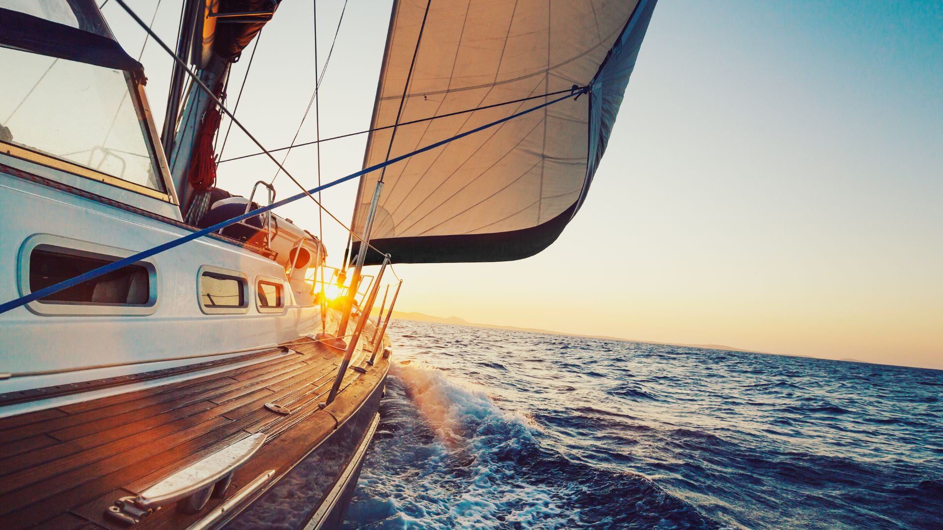 Sailboat gliding on open water at sunset, with sunlight shining through the sails and waves splashing—one of the best things to do in Tamarindo for an unforgettable coastal adventure.