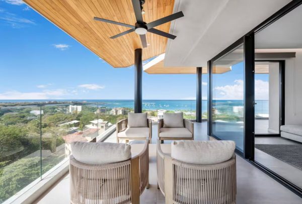 Modern balcony with four outdoor armchairs overlooking the ocean and coastline.